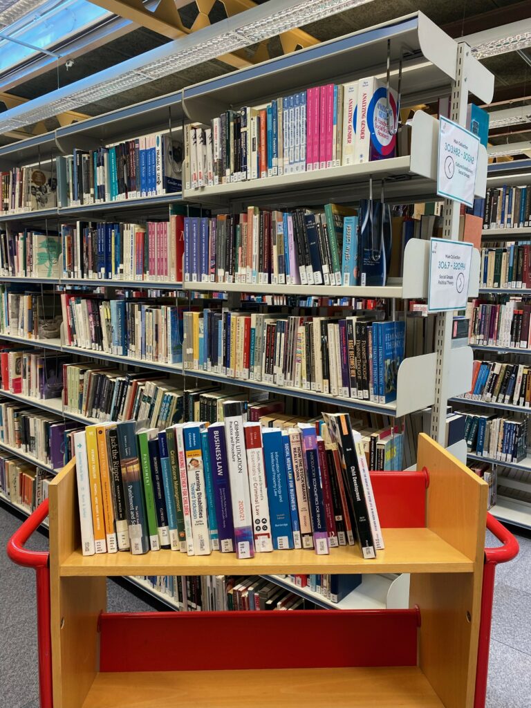 Trolley with books in front of a shelving unit with books on